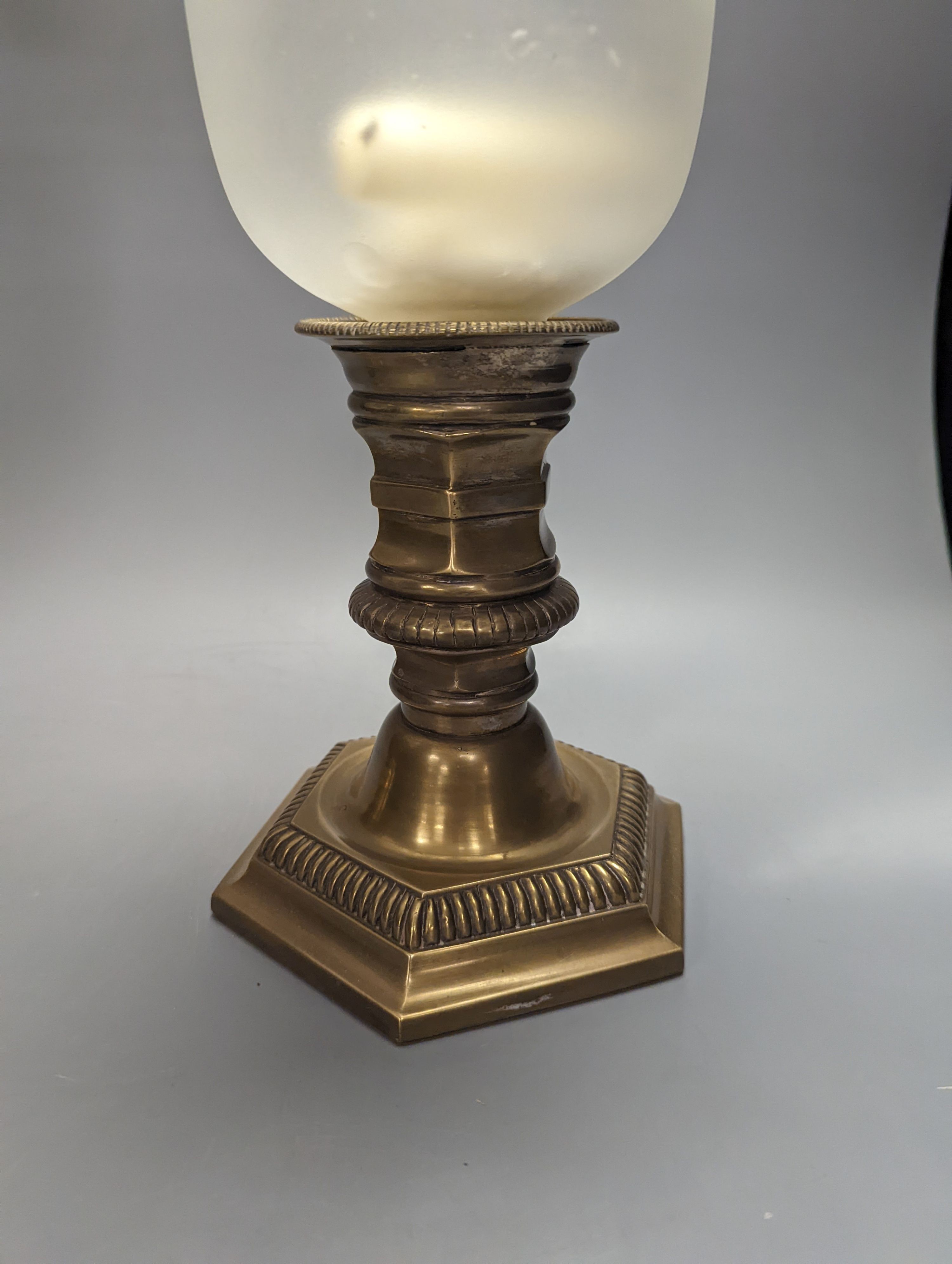 A pair of brass lamps with part frosted glass storm shades, height 45cm